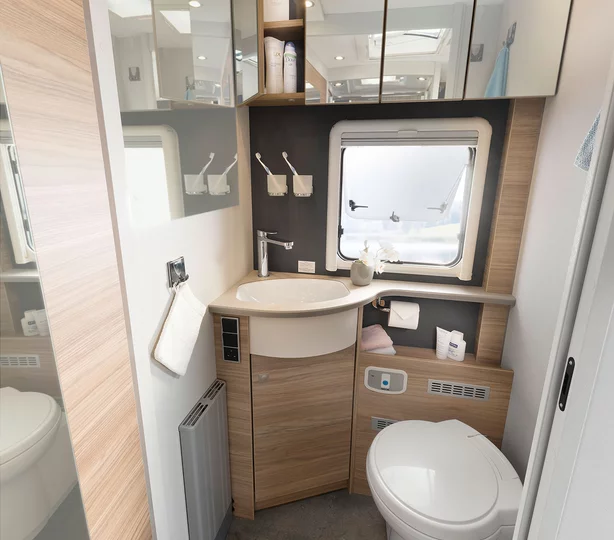 Modernes Bad im Dethleffs Alpa A 7820-2 Wohnmobil: Waschbecken, Toilette, Spiegelschränke und Fenster für helles, komfortables Ambiente auf Reisen.
