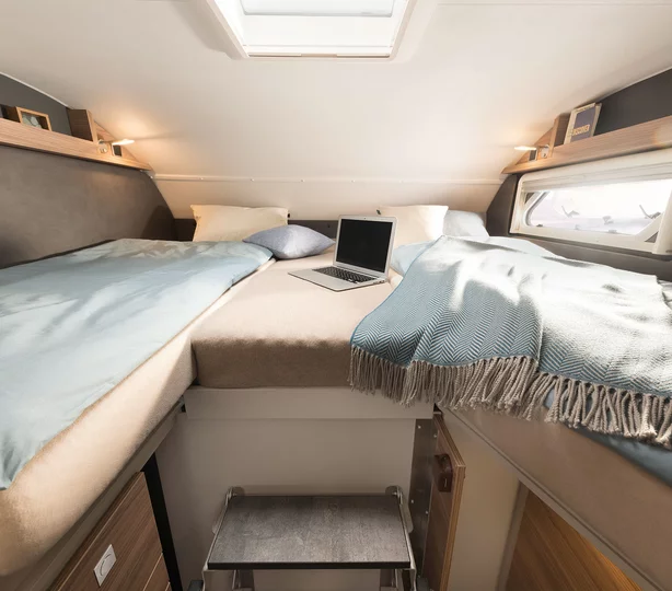 Schlafbereich im Dethleffs Alpa A 7820-2 Wohnmobil: komfortable Einzelbetten mit Mittelbrücke, Dachfenster, Seitenfenstern und gemütlicher Bettwäsche – ideal für entspanntes Reisen und Schlafkomfort im Wohnmobil.