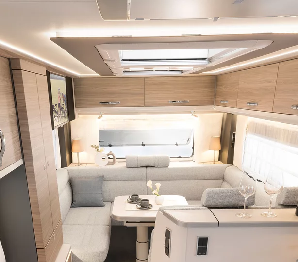 Wohnbereich im Dethleffs Alpa A 7820-2 Wohnmobil: moderne U-Sitzgruppe mit hellem Polster, Ober- und Unterschränken in Holzoptik, LED-Ambientebeleuchtung und Dachfenster für maximalen Komfort unterwegs.