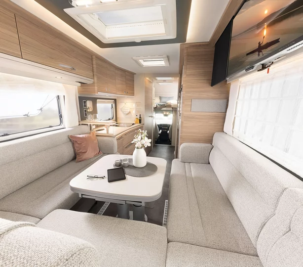 Großzügiger Wohnbereich im Dethleffs Alpa A 7820-2 Wohnmobil: moderne Einbauschränke in Holzoptik, helle LED-Beleuchtung, große Dachfenster und elegante Küche für maximalen Komfort auf Reisen.